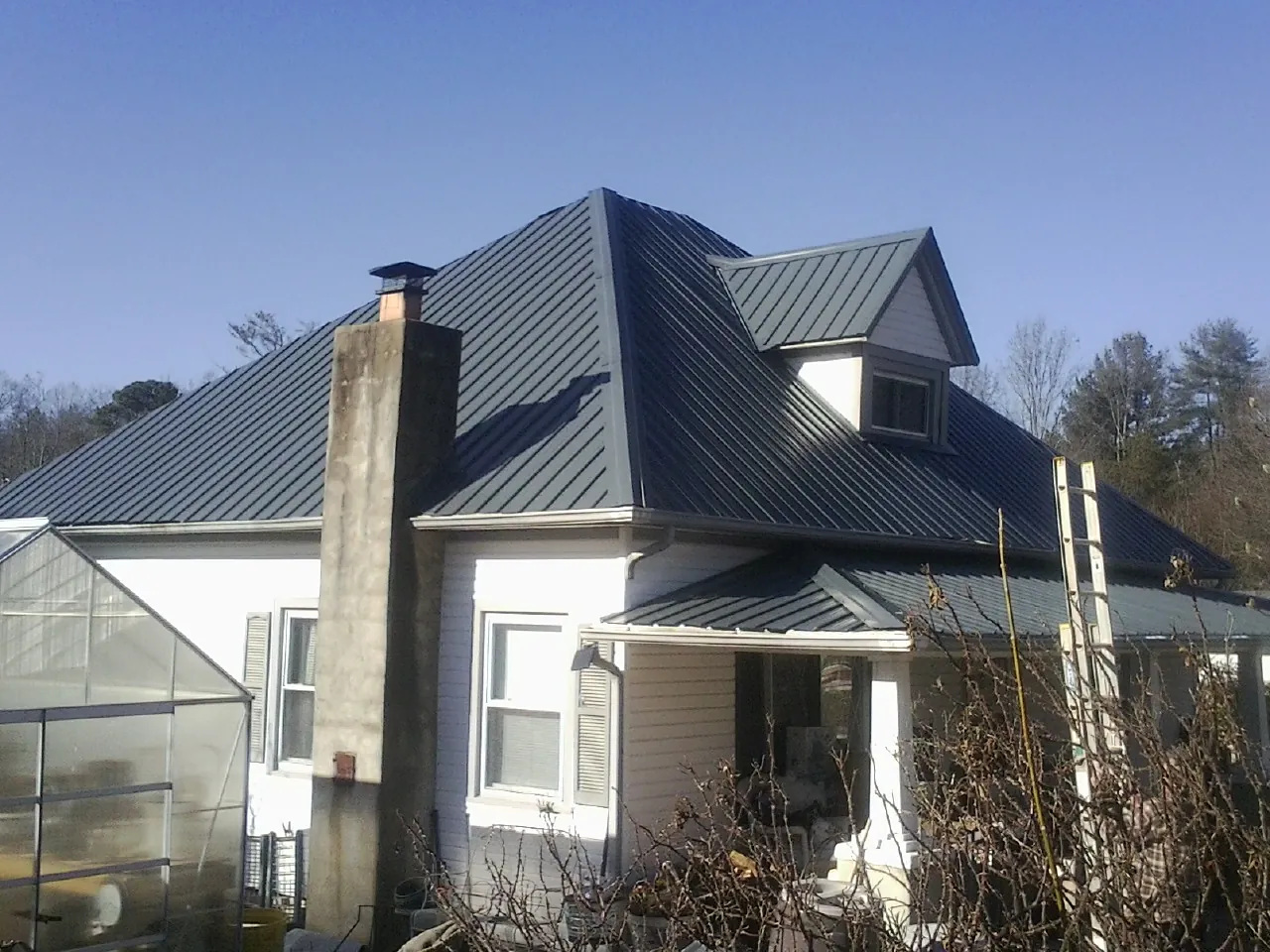 Dark blue standing seam metal roof on a white farmhouse with dormer — Slate & Tile Roof Repair by Roofing Brothers in Burnsville