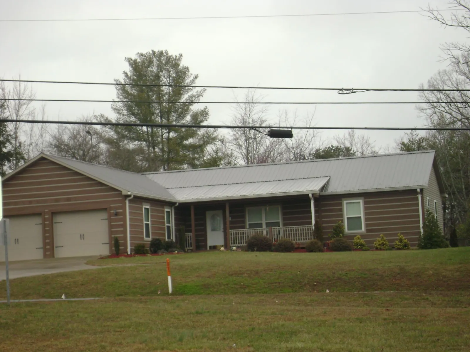 Gray metal roof on a log sided ranch home with a front porch in Burnsville